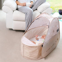 Load image into Gallery viewer, Pop Up Travel Cot with blackout cover, shown in a home
