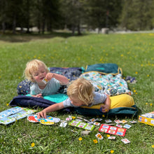 Load image into Gallery viewer, Two children in a field playing a card game whilst in their Toddler Bundle Beds Camping and Sleepover Beds, in Space and Adventure Designs. The best camping and sleepover toddler bed