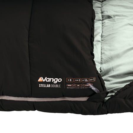 Close-up of a black Vango Stellar Double sleeping bag showing the black outer shell, zipper, interior lining, and printed product label.