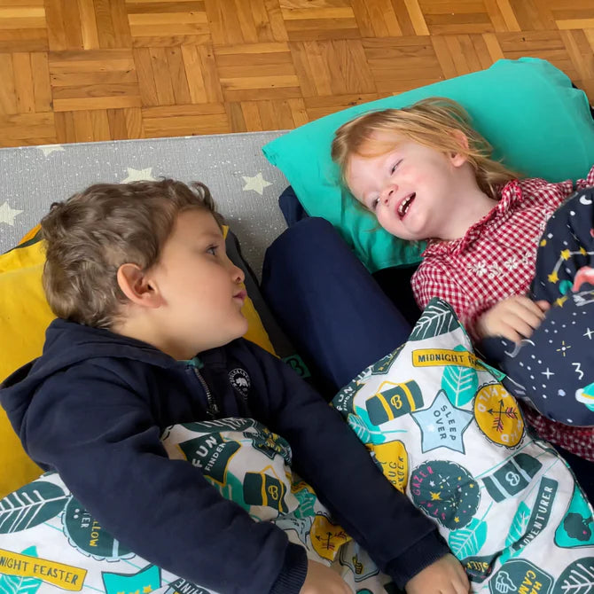 Boy and girl chatting in their Toddler Bundle Beds Camping and Sleepover Beds, in Space and Adventure Designs. The best camping and sleepover toddler bed
