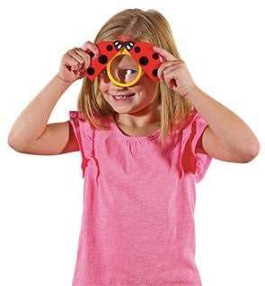 Girl looking through Ladybird Magnifier, children's magnifying toy for camping