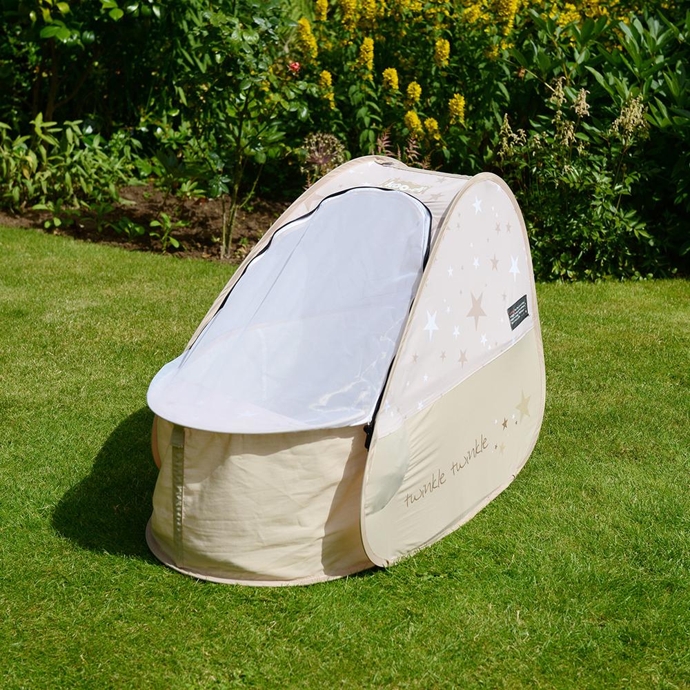 Pop Up Travel Cot with blackout cover, shown on grass