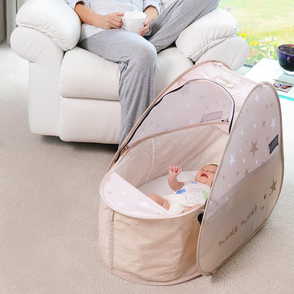 Pop Up Travel Cot with blackout cover, shown in a home